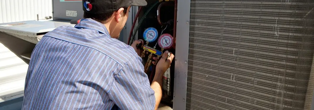 HVAC technician servicing a condenser unit in Eudora
